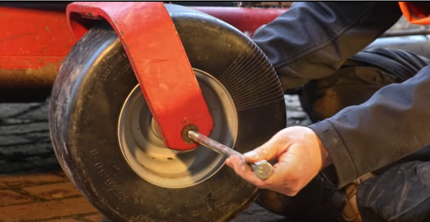 Installing a new zero turn mower front wheel by inserting the axle bolt through the frame and wheel