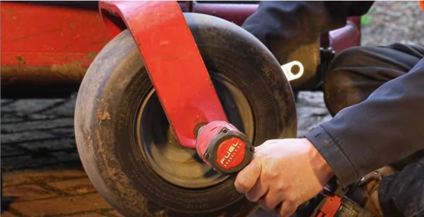 Removing the front wheel nut from a zero turn mower using a socket wrench