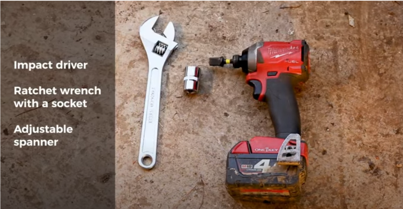 Tools required to change a zero turn mower front wheel including an impact driver, ratchet wrench with socket, and adjustable spanner